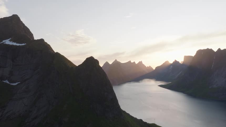 Landscape of sea surrounded by rocky mountains with sunrise on the horizon