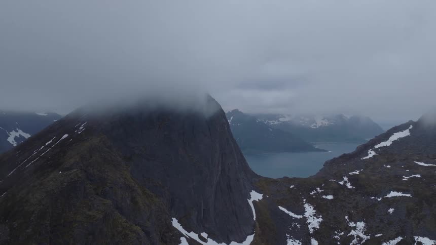 Aerial landscape of snowy mountains by the sea on a cloudy day