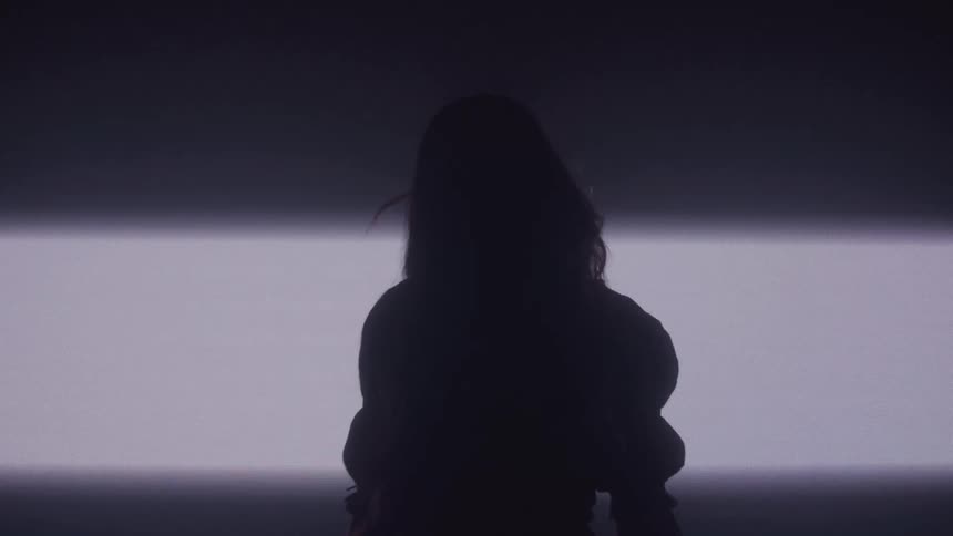 Silhouette of a woman with long hair in a dark room