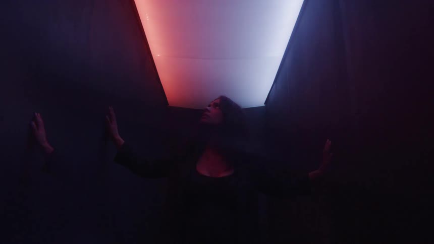 Woman in a narrow room with colored lights on the ceiling