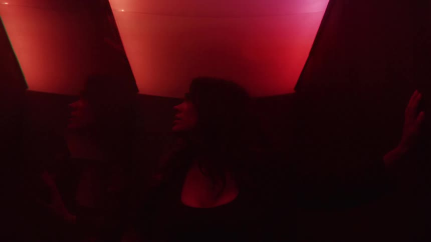 Two women in a nightclub with a dark atmosphere and flickering lights