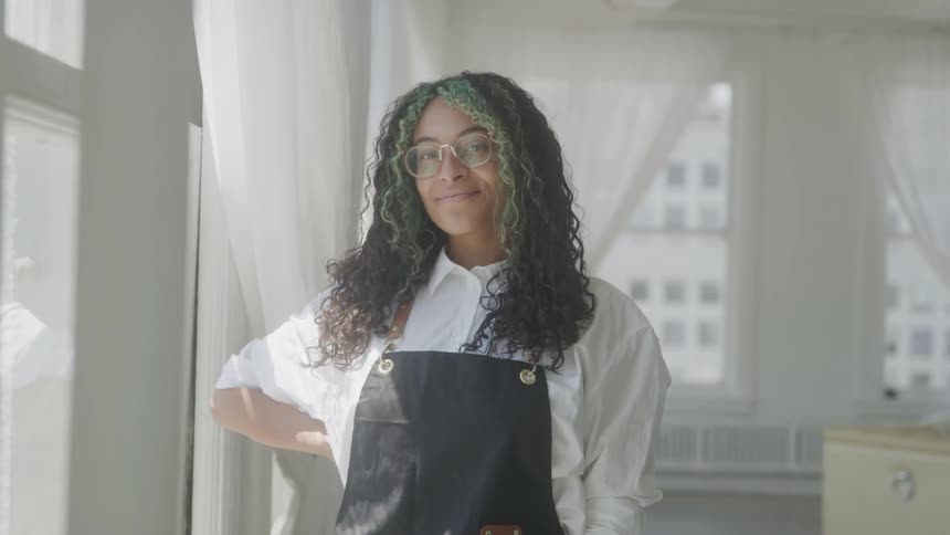 Portrait of a young black female waiter standing in a room during daytime