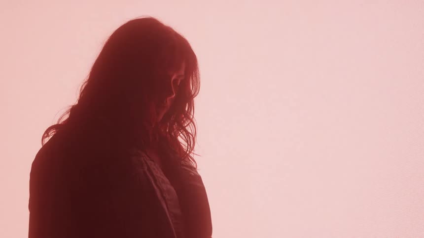Silhouette of a woman in a dark room with light in the background