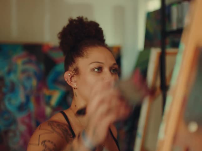 Close up of a young female artist painting canvases in an art studio during daytime