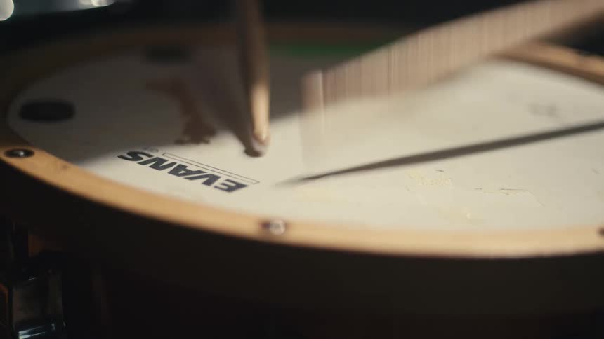 A drummer continuously hitting the drum with a stick
