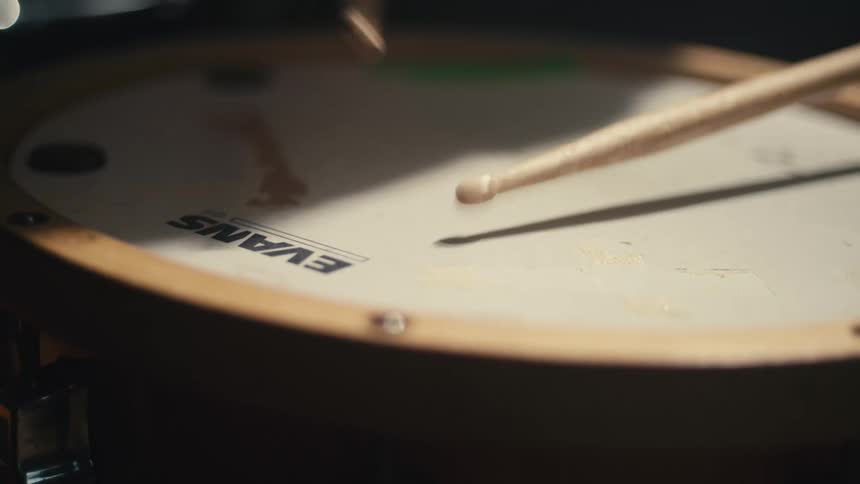 A drummer continuously hitting the drum with a stick