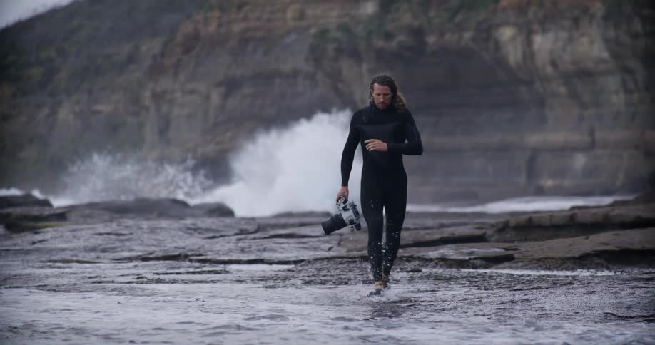 Man with duck parts and a professional camera running on the beach