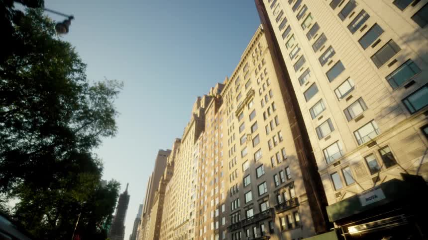 Tall apartment buildings line the street under clear daylight