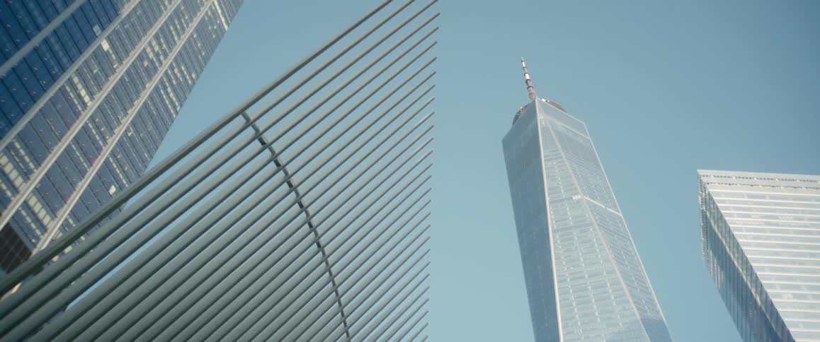 Modern skyscraper towers over city framed by buildings and beams