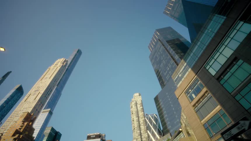 Wide shot of modern skyline with tall reflective skyscrapers under blue sky