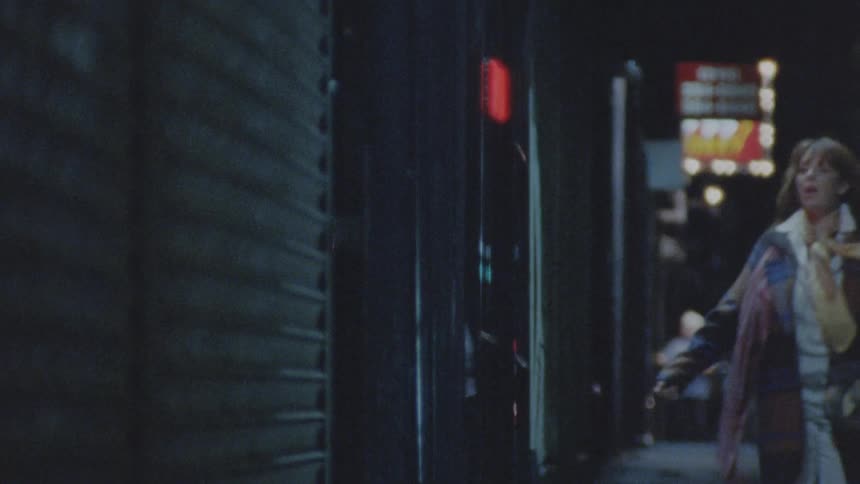 The video shows two people walking the first person is a man in a dark jacket and he walks toward the left side of the frame the second person is a woman with red hair and a patterned scarf she walks toward the right passing the man