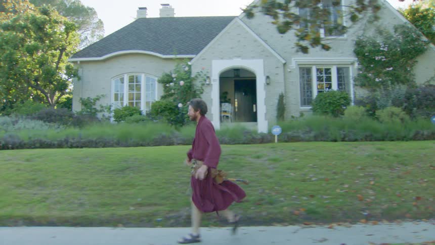 The man is walking fast through his neighborhood