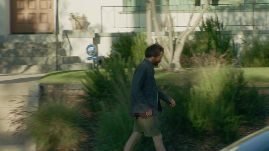 The man walks down the sidewalk in the neighborhood