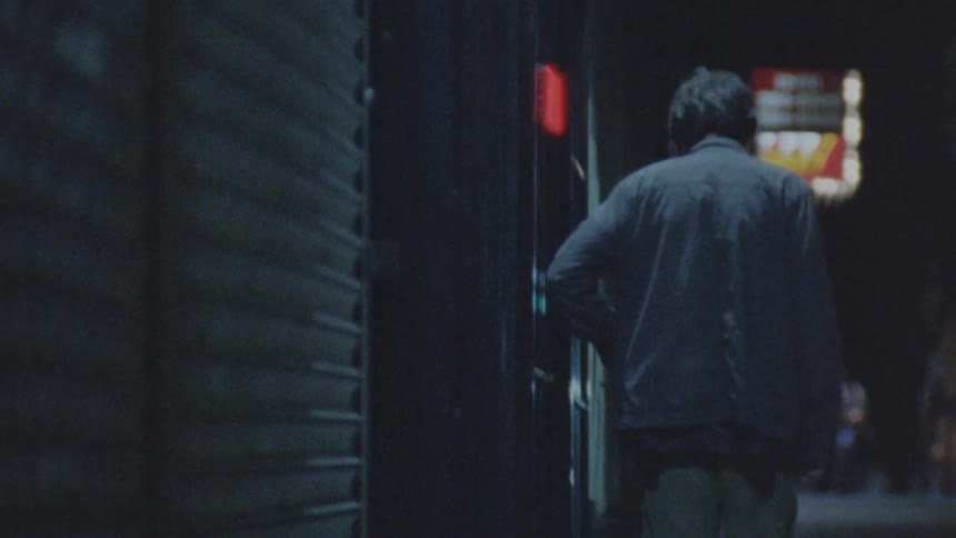 The man walks towards the building to open the door