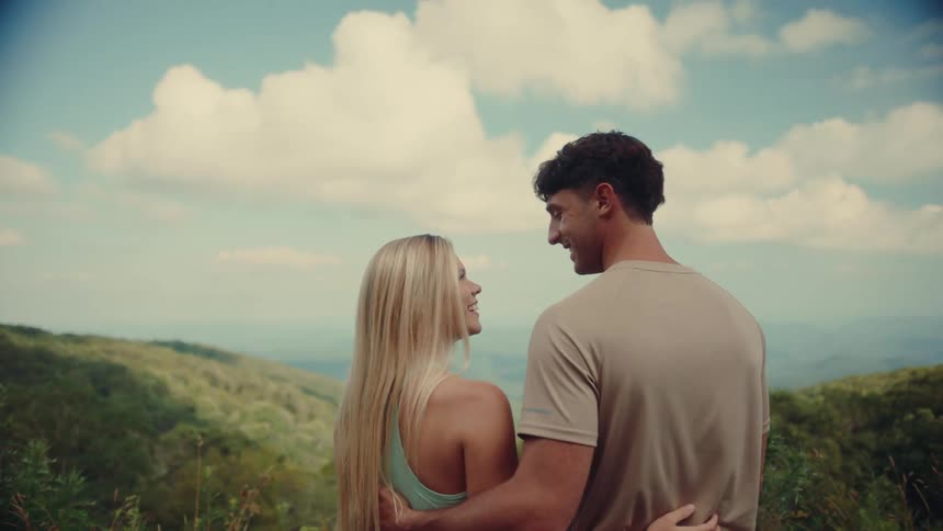 A man and woman kiss above the forest