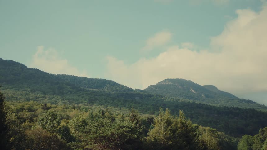 A scenic view of forest covered mountains under a clear sky