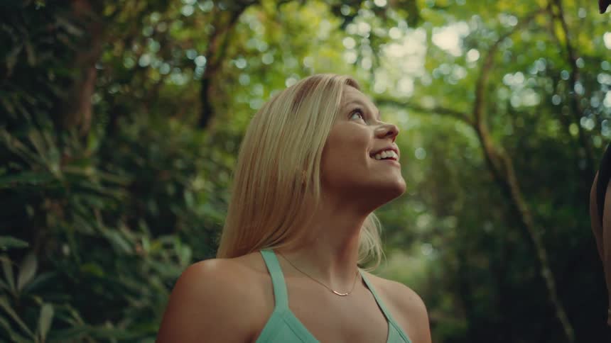 Woman smiles while looking up enjoying nature in a forest