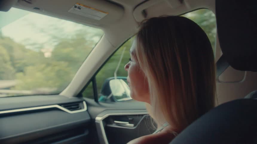 Woman in the passenger seat of a moving car talking happily