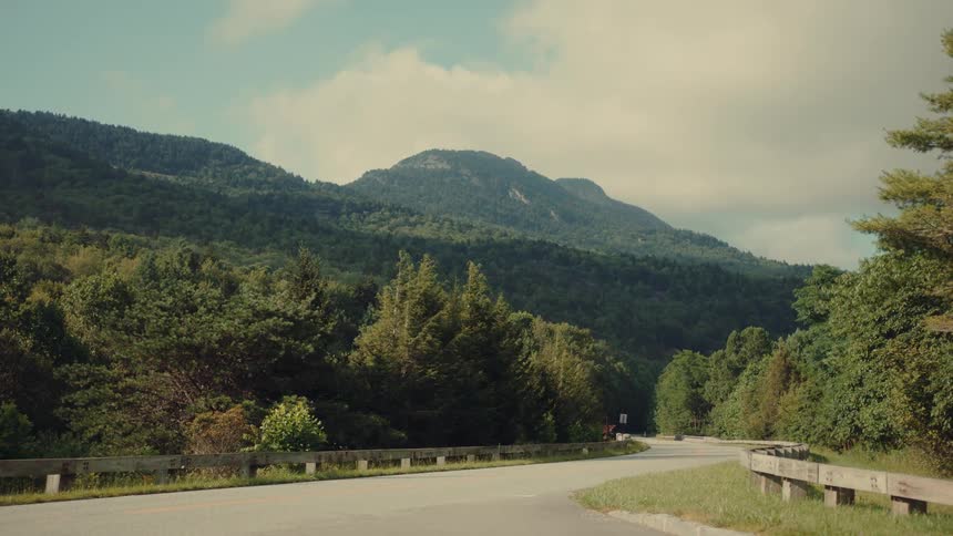 Paved road surrounded by a mountainous landscape with forest