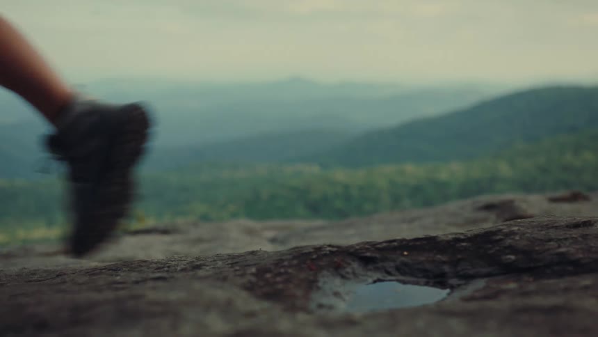 Hiking boots on a wet rock with mountains in the background