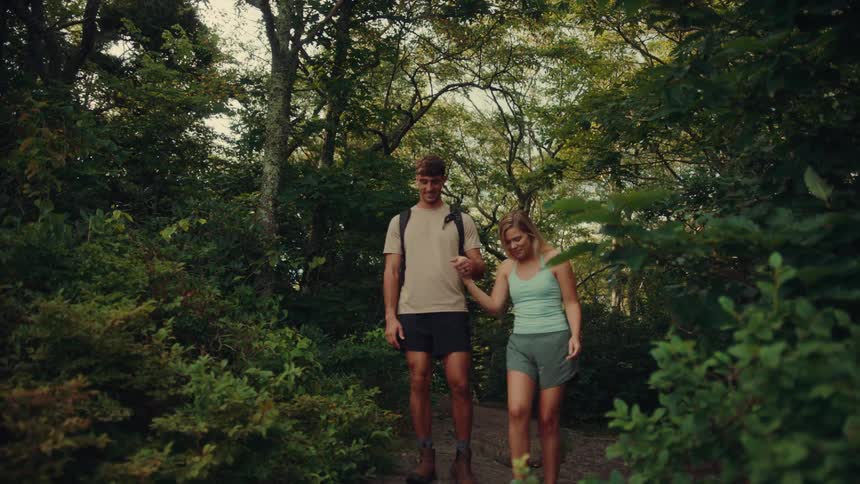 Husband and wife hiking on a trail through the forest