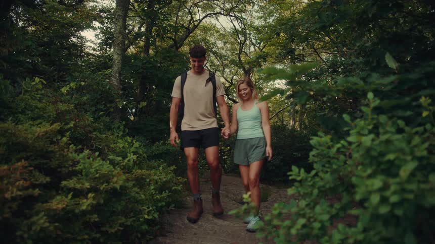 The man and woman hike down the trail in the forest