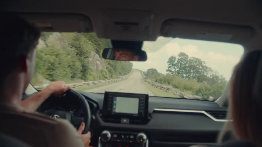A young couple are chatting while driving up the mountain in a forested area