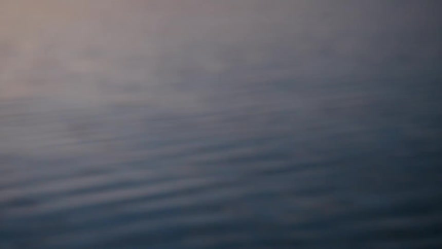 Gentle ripples spread across dusky water in fading light