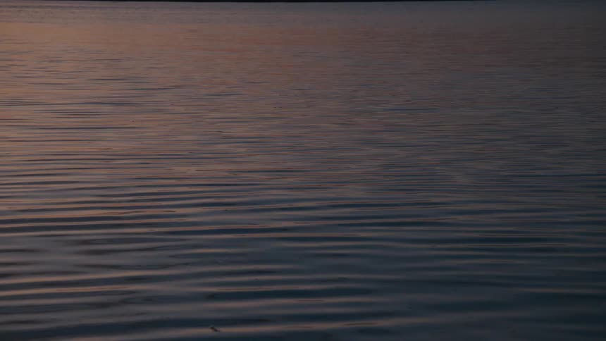 Calm ocean water with reflection of the dawn sun