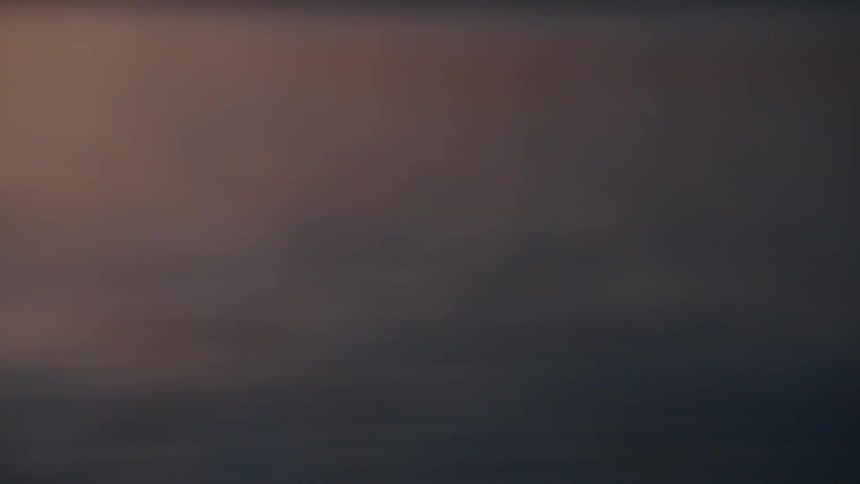 A calm blurry water surface reflects soft hues of twilight