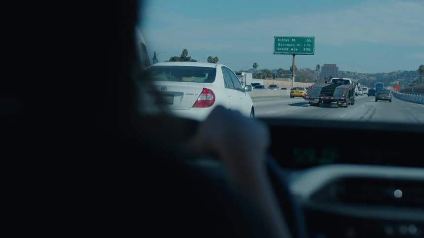 Woman with hands on steering wheel driving on a highway