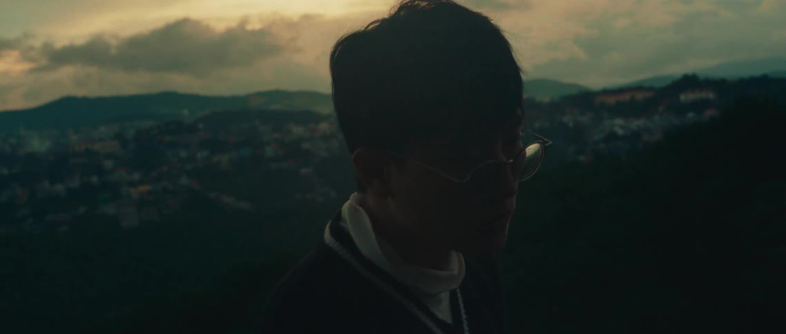 Man wearing glasses with panoramic view of mountains and houses in the background