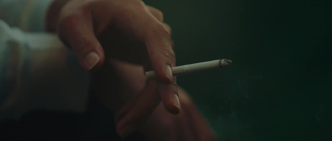 Persons hand holding a lit cigarette