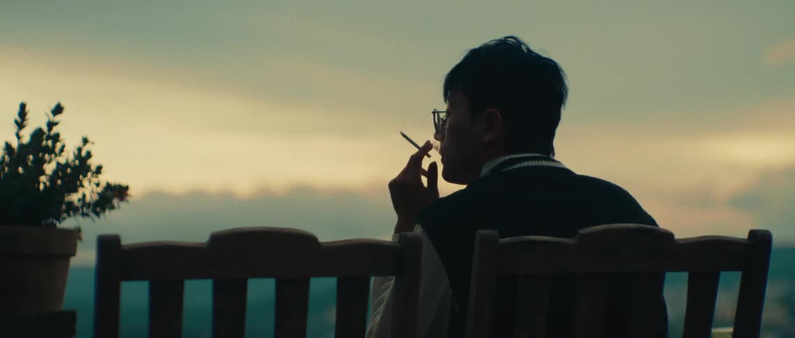 The man is sitting in a chair smoking