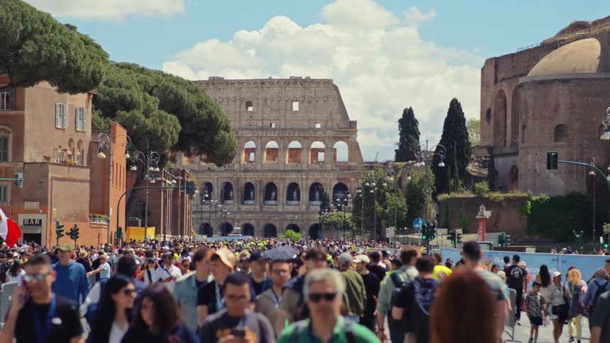 Crowd of people walk in a tourist area with the coliseum in the background