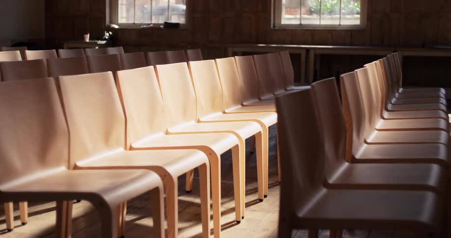 A church building with a series of chairs arranged in rows empty at midday
