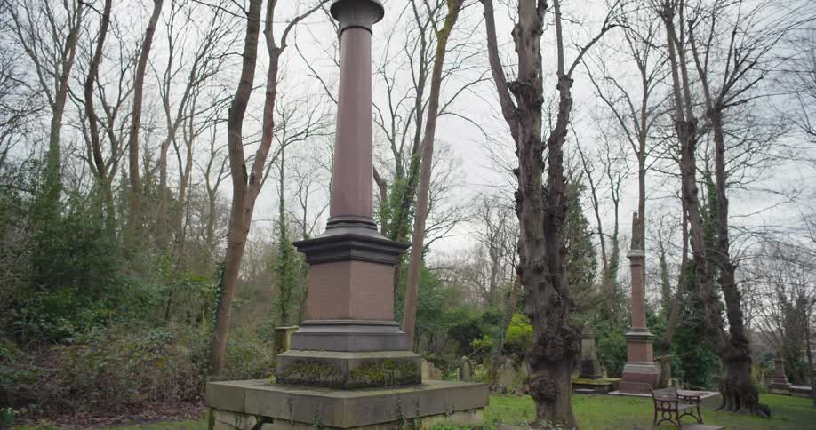 A graveyard with statue towers in a woodland area during daytime