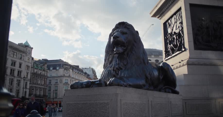 Pedestrians walk past the lion statue