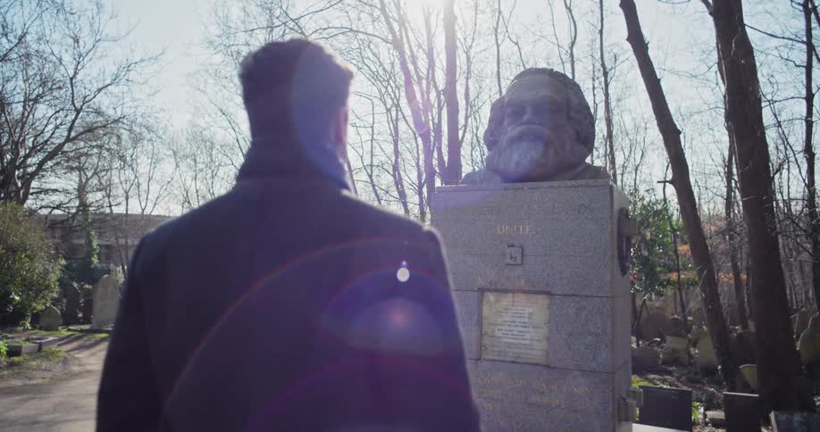 Man facing a statue of a person on a monument in the square