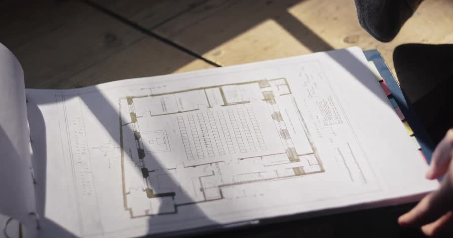 The architect is flipping through a book of blueprints