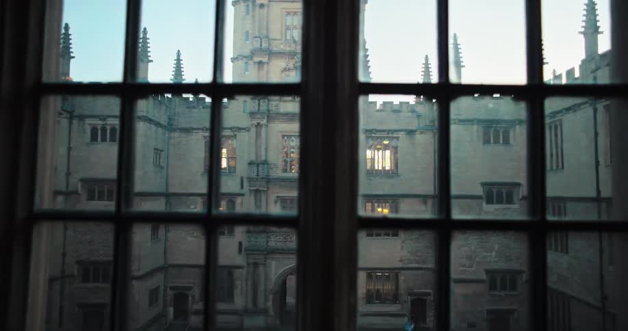 Windows show the arched entrance to the courtyard of a crenelation topped building