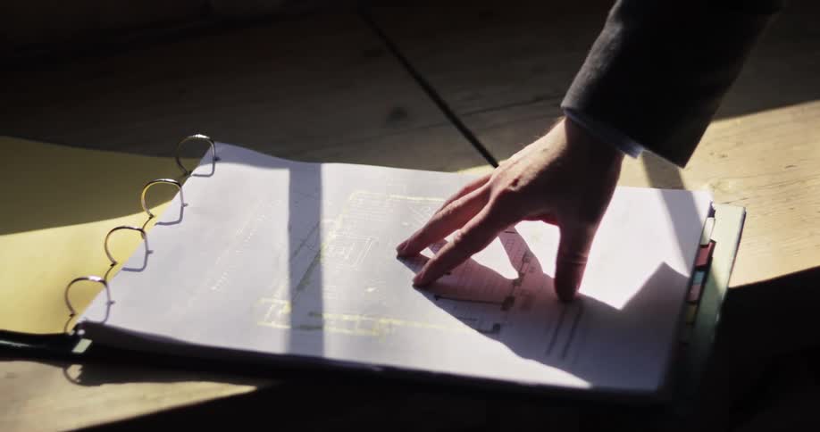 Person hand touches documents organized in a binder with colored dividers on the table