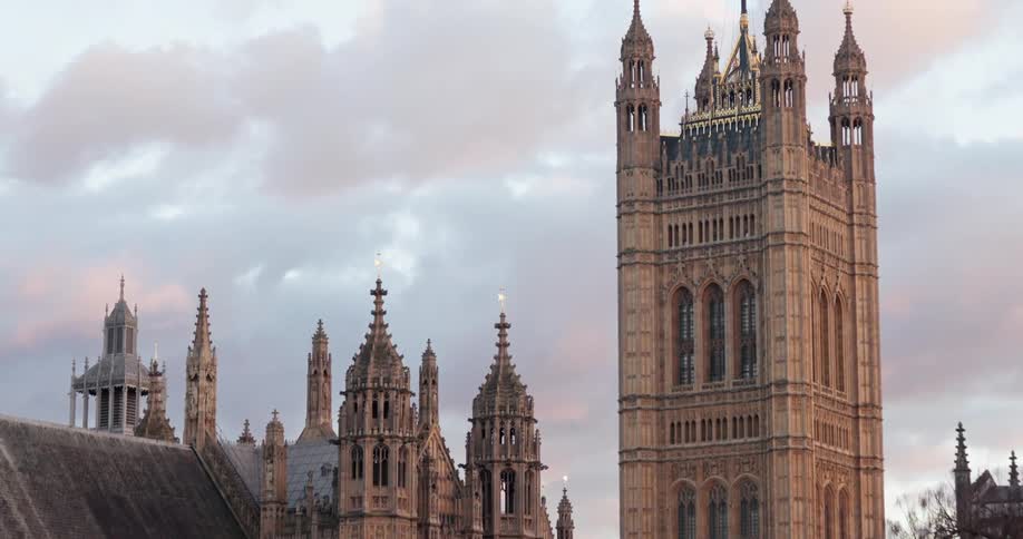 A tall stone building is in the city with people walking by