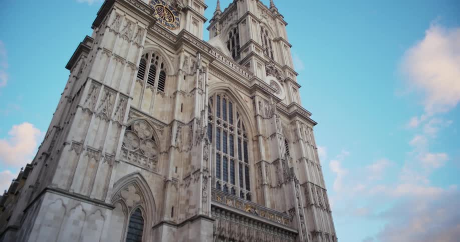 Facade of westminster abbey in london with its gothic towers and stained glass under a blue sky