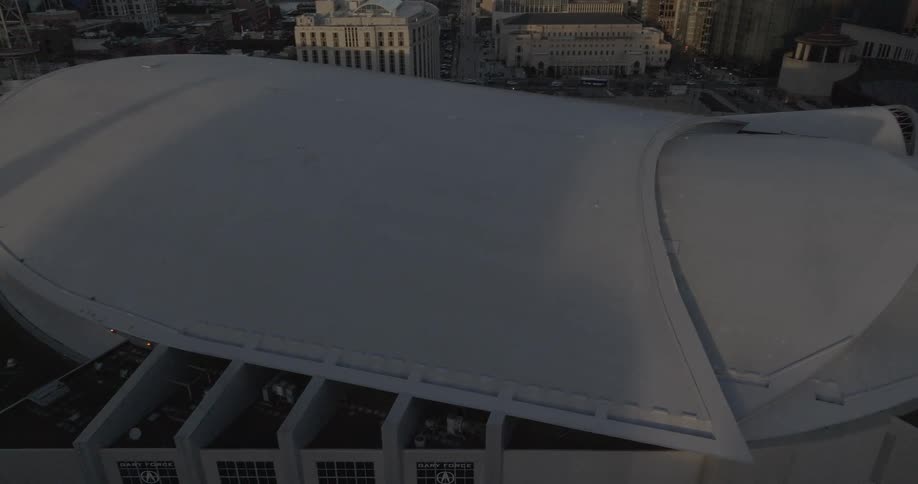 Aerial view of a large indoor arena with a white facade located in an urban area