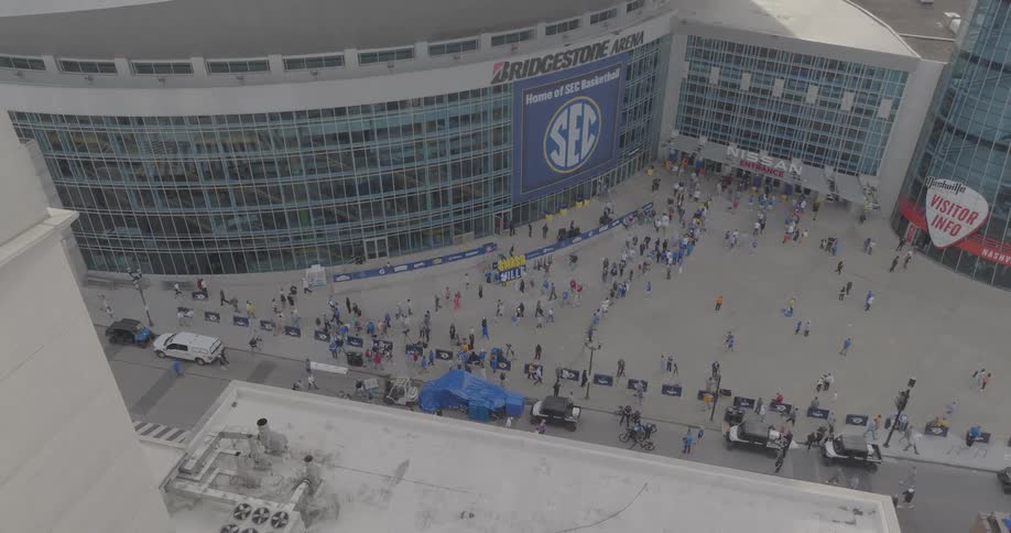 People gather in front of bridgestone arena in nashville decorated with sec basketball tournament banners
