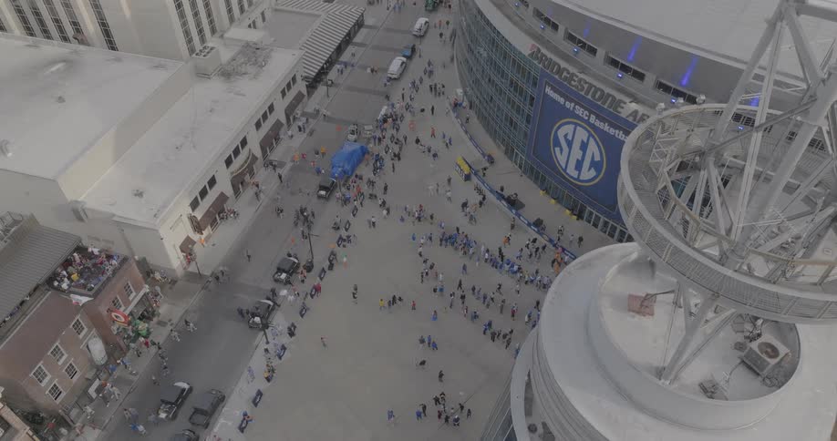A crowd gathers outside a stadium bearing the sec logo in an urban setting