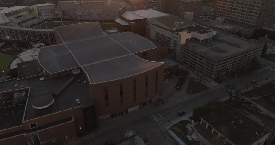Aerial cityscape at sunset with a stadium large buildings and surrounding parking structures