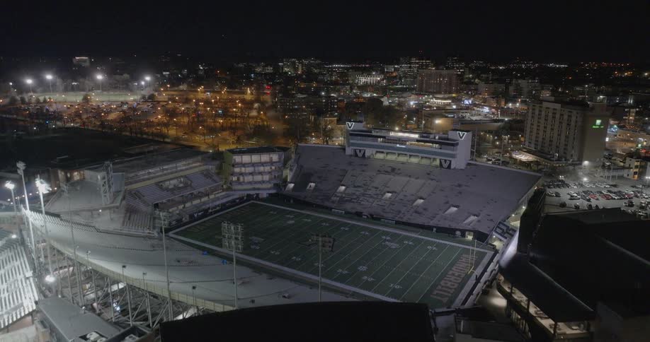 Empty football stadium at night with city lights in the background
