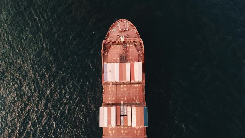 Aerial view of the bow of a cargo ship carrying colorful containers on the sea